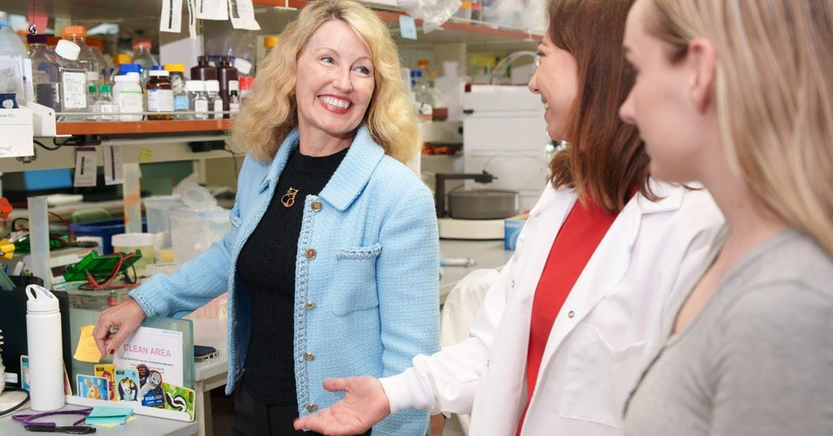 Woman on the left with a blue jacket having a conversation with two women on the right.